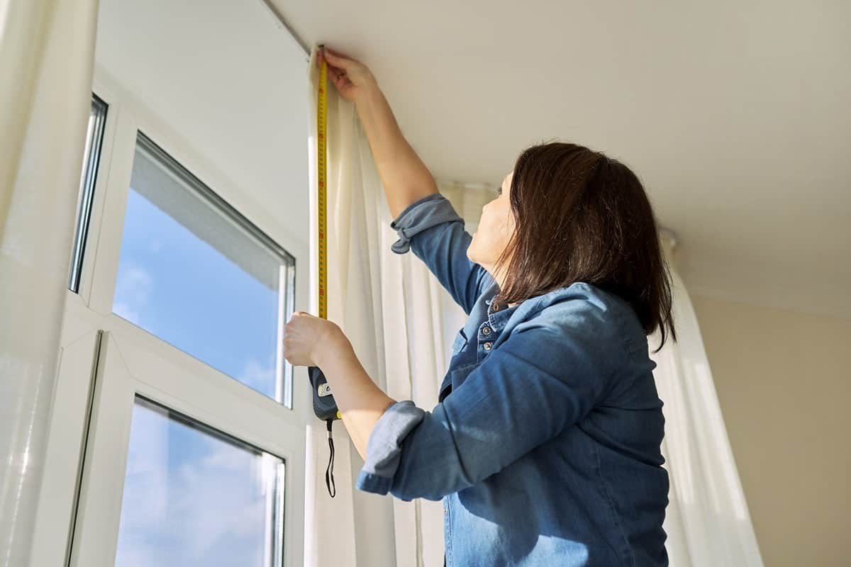 Image of a person measuring a window for curtains